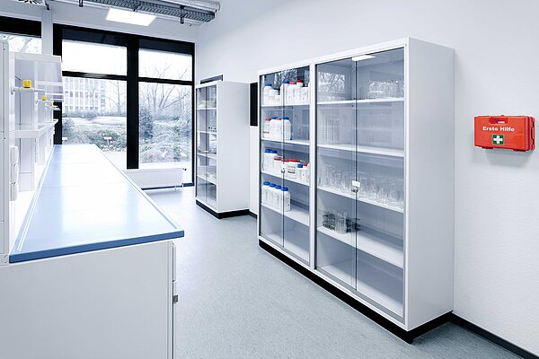 Übersicht über Laborregale mit Chemikalien und Glaswaren sowie einer Erste-Hilfe-Station im PTA-Ausbildungslabor der Ludwig Fresenius Schulen Dortmund.